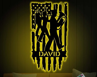 May include: A black metal silhouette of marching band members playing instruments in front of an American flag design. The silhouette is illuminated with a yellow light. The name "DAVID" is written below the silhouette.