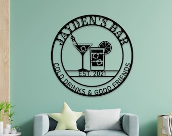 May include: Black metal sign with the text "Jayden's Bar" in a circle. The sign also includes the text "Cold Drinks & Good Friends" and "Est. 2021" with a cocktail glass and a glass of ice.
