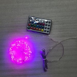 May include: A set of pink LED fairy lights with a remote control. The remote has 24 buttons, each with a different color LED light.