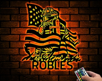 May include: A black silhouette of a firefighter holding an American flag with the name "ROBLES" underneath. The image is lit up in orange and yellow.
