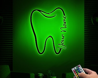 May include: Green neon sign shaped like a tooth with the text "Your Name" next to it. The sign is mounted on a wall and is illuminated. A remote control is in the foreground.
