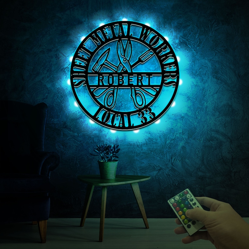 May include: A black metal sign with the words "Sheet Metal Workers" and "Local 33" around a pair of scissors and a hammer. The sign is illuminated with blue LED lights and has the name "Robert" in the center.
