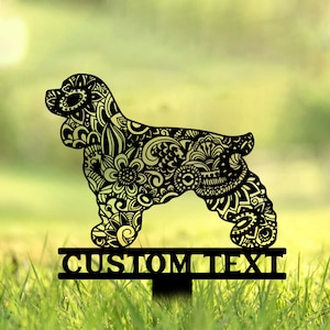 May include: Black metal silhouette of a cocker spaniel dog with intricate floral patterns. The silhouette is attached to a metal stake with a sign that reads "CUSTOM TEXT".