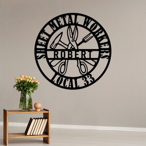 May include: Black metal sign with the words "Sheet Metal Workers" and "Local 33" around a circle. The name "Robert" is in the center of the circle, with a hammer, screwdriver, and scissors inside the circle.