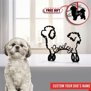 May include: Black metal silhouette of a dog with the name "Bailey" written underneath. The silhouette is standing on a white surface. A small white dog is sitting in the foreground. The text "FREE GIFT" and "CUSTOM YOUR DOG'S NAME" are also visible.