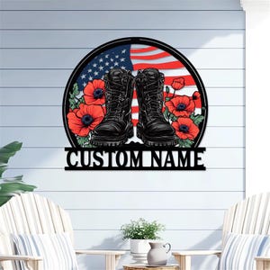 May include: A black metal sign featuring combat boots, red poppies, and an American flag design. The sign is in a circular shape with the text "CUSTOM NAME" at the bottom. The boots are centered, with the flag and flowers behind them.