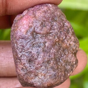 Puede incluir: Una piedra preciosa de rubí rosa oscuro en bruto con un acabado natural sin pulir.