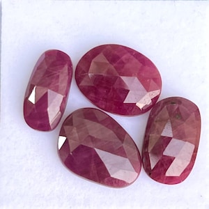 May include: Four faceted ruby gemstones in a variety of sizes and shapes. The gemstones are a deep red color and have a polished finish.