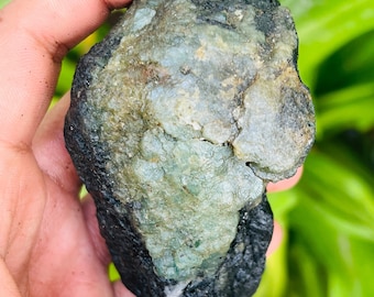 May include: A rough, dark gray rock with a large, light green, crystalline section. The rock has a rough, uneven surface.