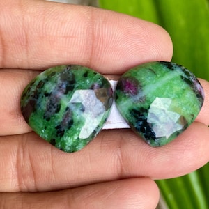 Peut inclure: Deux pierres précieuses vertes en forme de cœur avec une taille facetée. Les pierres ont un mélange de couleurs vertes, noires et blanches.