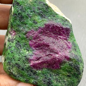 以下が含まれることがあります： 鮮やかな色の組み合わせが特徴の原石。石の中心には鮮やかなマゼンタ色があり、緑と黒のテクスチャで囲まれています。 全体的に自然で未加工の外観です。
