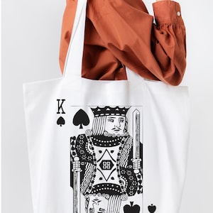 May include: White canvas tote bag with a black and white illustration of the King of Spades playing card.