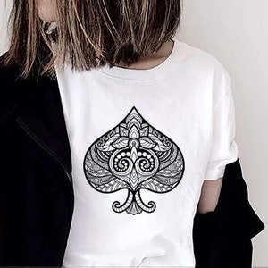 May include: A white t-shirt with a black and white graphic of a spade playing card. The spade is intricately designed with a floral pattern.