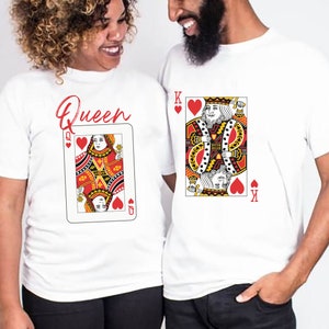 May include: A couple wearing white t-shirts with a playing card design. The woman's shirt says "Queen" and features the Queen of Hearts. The man's shirt features the King of Hearts.