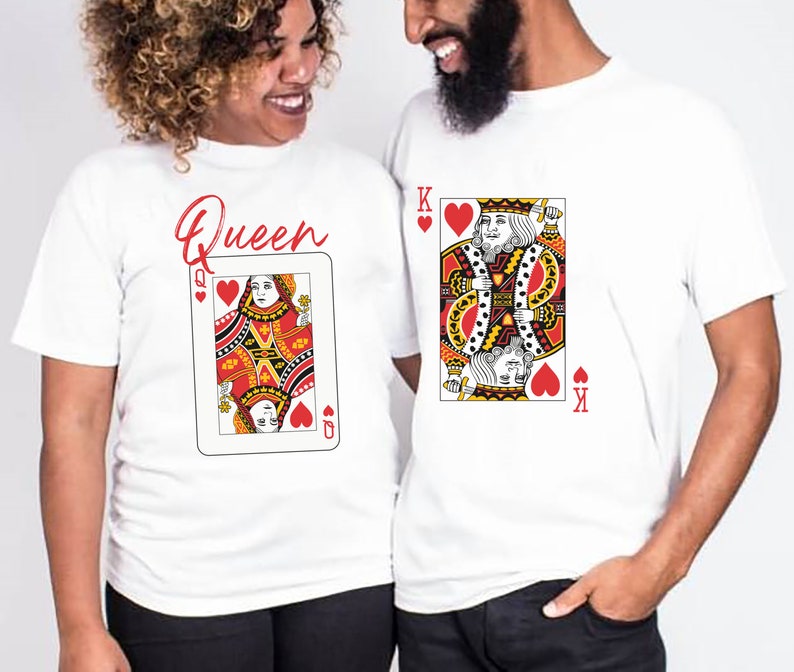 May include: A couple wearing white t-shirts with a playing card design. The woman's shirt says "Queen" and features the Queen of Hearts. The man's shirt features the King of Hearts.