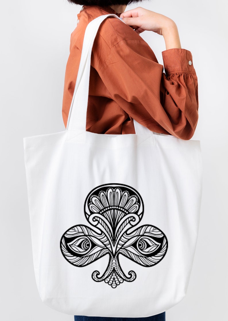 May include: A white tote bag with a black and white illustration of a stylized clover with eyes. The clover is a common symbol for good luck.