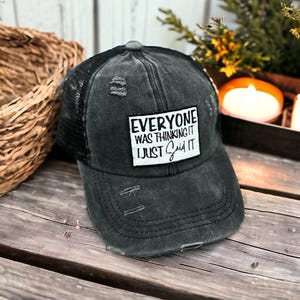 May include: A charcoal gray distressed baseball cap with a black mesh back. A rectangular white patch on the front features the black text: EVERYONE WAS THINKING IT I JUST SAID IT. The cap has a curved brim and visible frayed fabric details.