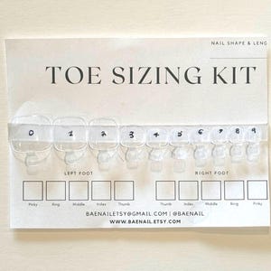 Op de afbeelding: Een witte kaart met de tekst "TOE SIZING KIT" in zwart. De kaart heeft een rij van tien doorzichtige kunststof teennagel-maatlijsten die zijn gelabeld met de nummers 0 tot en met 9. Onder de maatlijsten bevinden zich twee rijen van vijf witte vierkanten die zijn gelabeld met de namen van de tenen: pink, ringvinger, middelvinger, wijsvinger en duim. De kaart bevat ook de tekst "LEFT FOOT" en "RIGHT FOOT" en de contactgegevens "BAENAILETSY@GMAIL.COM | @BAENAIL WWW.BAENAIL.ETSY.COM".