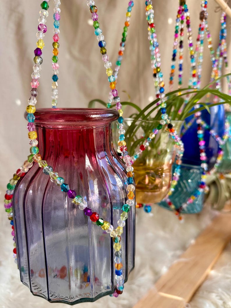 May include: A set of glass vases with colorful beaded hangers. The vases are clear and have a textured surface. The beads are multi-colored and create a rainbow effect.