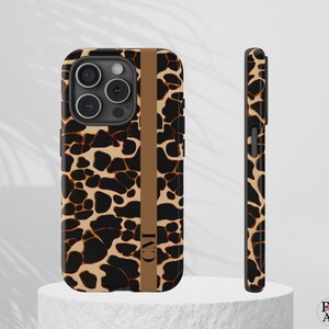 May include: A phone case with a brown and black animal print design. The case has a vertical brown stripe with the initials "CMI". The case is shown from the front and side.