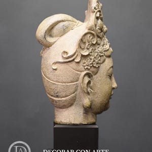 May include: A white ceramic sculpture of a woman's head with a detailed crown and elaborate hairstyle. The sculpture is on a black pedestal.