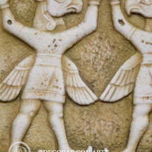 May include: A close-up of a relief sculpture depicting two winged human figures with animal heads. The figures are facing each other and have their arms raised. The sculpture is made of a light-colored stone and has a textured surface.