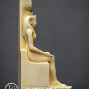 Puede incluir: Una escultura de m&aacute;rmol blanco de una diosa egipcia sentada en un trono. La diosa lleva un tocado y una t&uacute;nica larga. La escultura est&aacute; en posici&oacute;n sentada con las piernas cruzadas. La escultura est&aacute; sobre un pedestal blanco.
