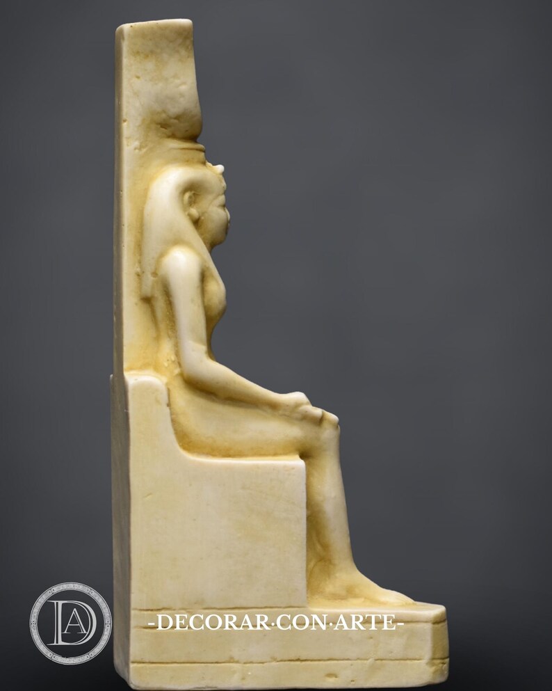 Puede incluir: Una escultura de m&aacute;rmol blanco de una diosa egipcia sentada en un trono. La diosa lleva un tocado y una t&uacute;nica larga. La escultura est&aacute; en posici&oacute;n sentada con las piernas cruzadas. La escultura est&aacute; sobre un pedestal blanco.