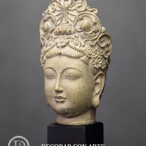 May include: A white and gold ceramic sculpture of a Buddha head with a detailed crown. The sculpture is on a black base.