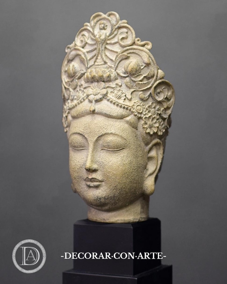 May include: A white and gold ceramic sculpture of a Buddha head with a detailed crown. The sculpture is on a black base.