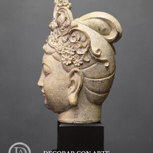 May include: A white ceramic sculpture of a woman's head with a detailed crown and a bun. The sculpture is on a black base.