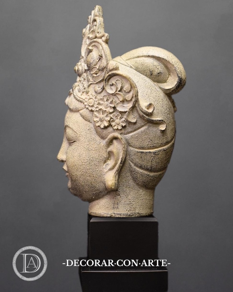 May include: A white ceramic sculpture of a woman's head with a detailed crown and a bun. The sculpture is on a black base.