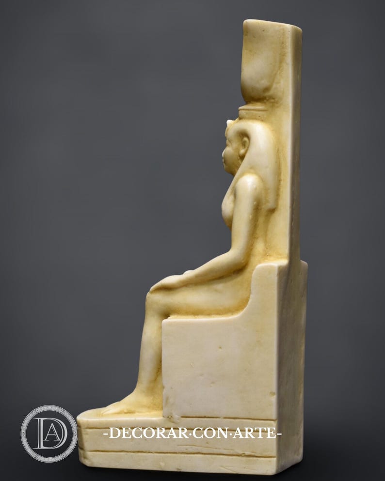 Puede incluir: Una estatua blanca sentada de una diosa egipcia con un alto tocado. La estatua est&aacute; hecha de un material liso y pulido y est&aacute; sentada en un trono. La diosa lleva una larga t&uacute;nica fluida y tiene una expresi&oacute;n serena en su rostro.