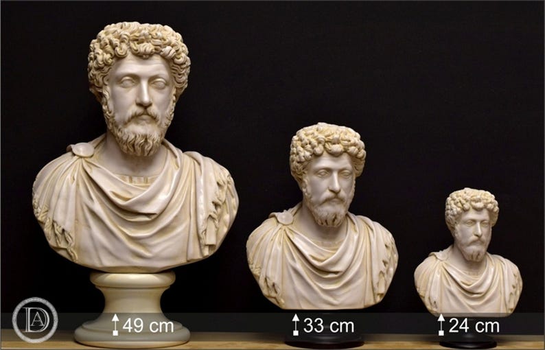May include: Three white marble busts of the Roman emperor, Marcus Aurelius, in different sizes. The busts are on black bases. The largest bust is 49 inches tall, the middle bust is 33 inches tall, and the smallest bust is 24 inches tall.
