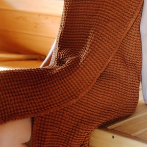 May include: A waffle weave robe in a rust brown colour. The robe is made of a soft, absorbent material and is perfect for lounging around the house.
