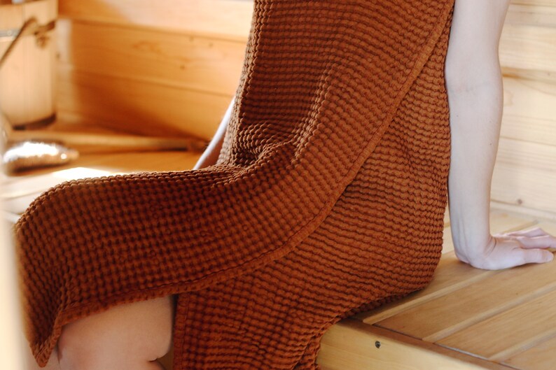 May include: A waffle weave robe in a rust brown colour. The robe is made of a soft, absorbent material and is perfect for lounging around the house.