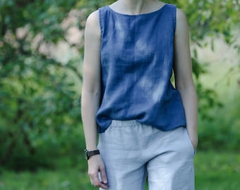 Puede incluir: Una blusa azul sin mangas con un amplio escote barco y corte holgado, combinada con un pantalón gris claro con cintura elástica y bolsillos laterales. La blusa tiene una textura tejida visible y el pantalón un acabado liso y claro.