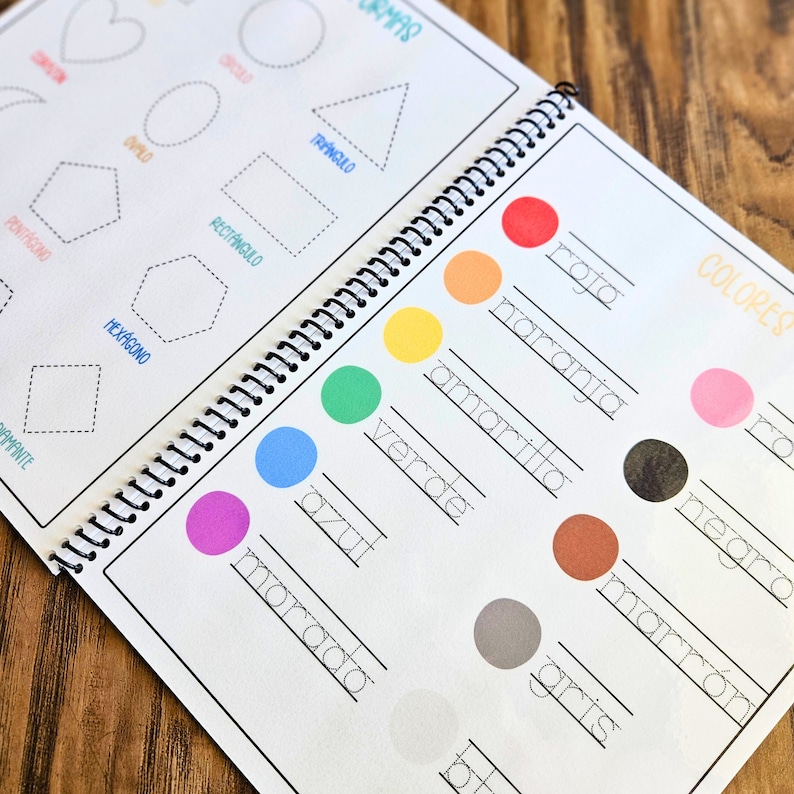 May include: A spiral-bound educational workbook featuring two pages of learning activities. The left page displays dashed outlines of geometric shapes with labels. The right page shows colored circles next to Spanish words for colors with lines for writing.