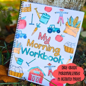 May include: A spiral-bound workbook with a colourful farm-themed cover. The cover features illustrations of a tractor, apples, corn, and a scarecrow. The title "My Morning Workbook" is displayed prominently. The workbook includes the text "Dry-erase, Personalizable, 14 Activity Pages."