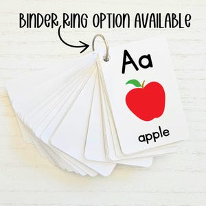 May include: A set of alphabet flash cards with a red apple illustration and the letter "Aa" and the word "apple" printed on the card. The cards are attached to a binder ring.