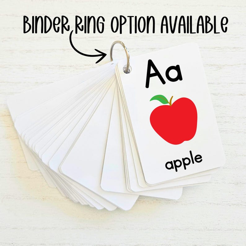 May include: A set of alphabet flash cards with a red apple illustration and the letter "Aa" and the word "apple" printed on the card. The cards are attached to a binder ring.