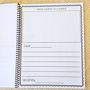 May include: Open notebook with lined pages and a spiral binding. The page features the text "Write a letter to a friend" at the top, with space for a drawing and lines for writing. The notebook is open on a light-colored surface.