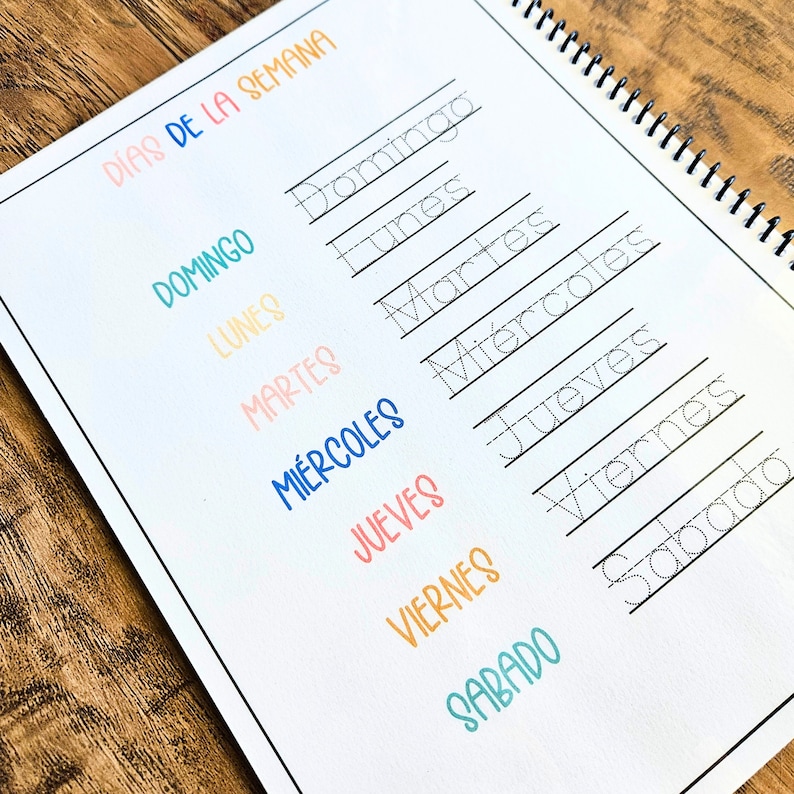 May include: A spiral-bound educational worksheet titled D&Iacute;AS DE LA SEMANA featuring a list of the days of the week in Spanish. The page includes colorful printed text and corresponding dotted-line words for tracing practice in black ink.