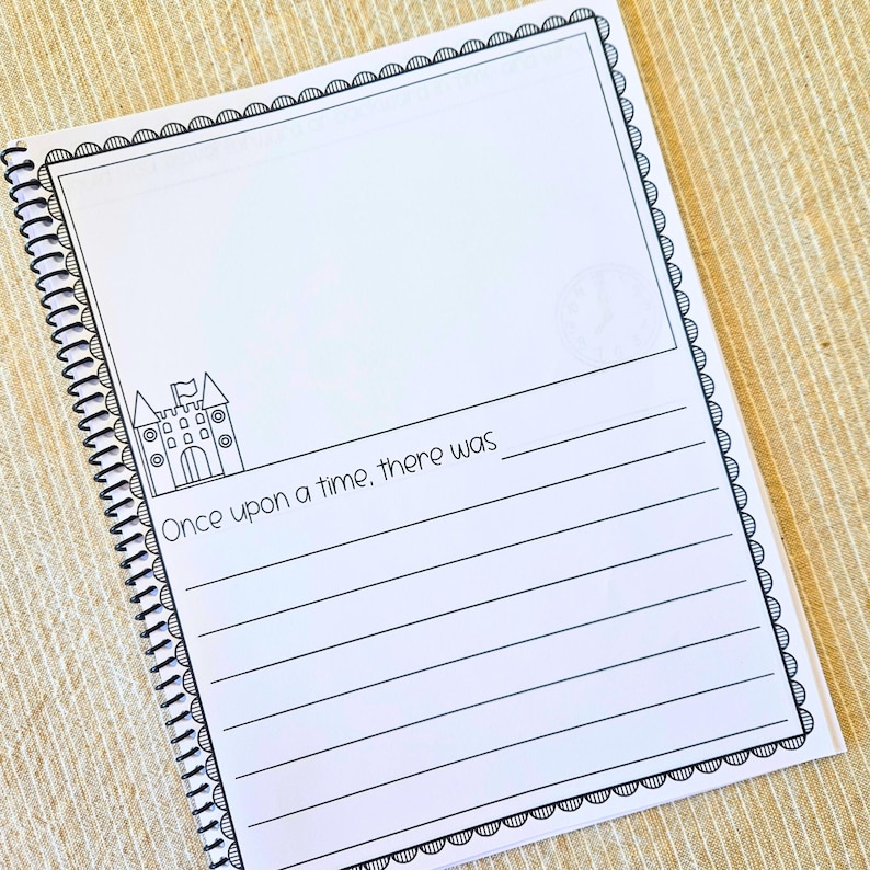 May include: A spiral-bound notebook with a white cover featuring a black border and the text "Once upon a time, there was". The notebook has a castle illustration and lined pages for writing.