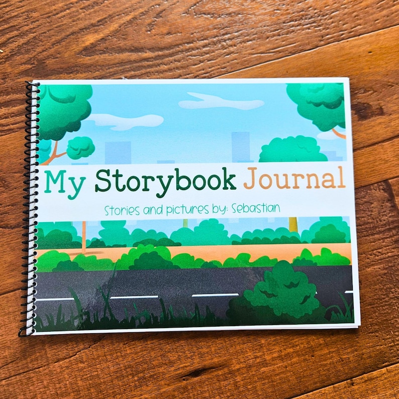 Może przedstawiać: Szyty spiralnie dziennik z kolorową okładką przedstawiającą scenę miejską z drzewami, drogą i tekstem "My Storybook Journal" oraz "Stories and pictures by: Sebastian".
