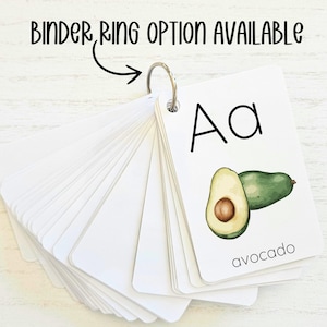 May include: A set of alphabet flash cards with a binder ring. The card shown features the letter "A" and a drawing of an avocado with the word "avocado" printed below.