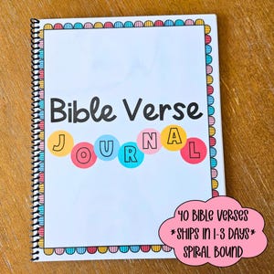 May include: A spiral-bound journal with the words "Bible Verse Journal" on the cover. The word "Journal" is spelled out in colorful circles. The journal has a decorative border and a pink cloud-shaped graphic with text.