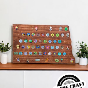 May include: A wooden geocaching display board with a brown stain. The board is shaped like the state of Minnesota. It has 5 rows of 8 round metal geocaching trackable tags. The board also has several small geocaching pins and a small wooden sign that says "CACHE CRAFT".