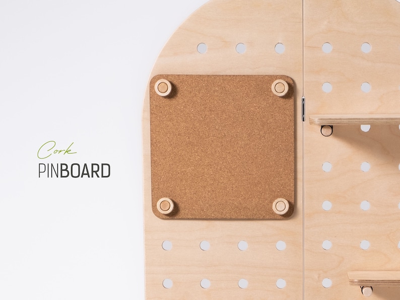 May include: A light wood pinboard with a cork board section. The cork board is surrounded by a light wood frame and has four small wooden knobs in the corners. The pinboard has a grid of holes for hanging items.