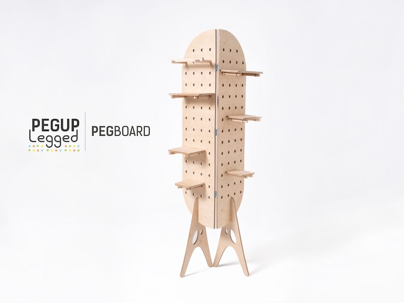 May include: A freestanding pegboard with five shelves and a rounded top. The pegboard is made of light brown wood and has a white background. The pegboard is labelled "PEGUP Legget PEGBOARD".